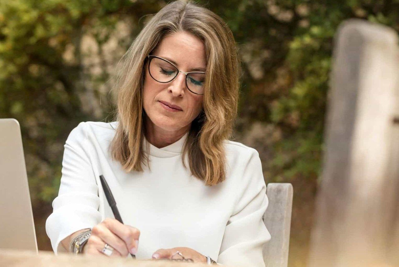 Starší žena v brýlích si píše poznámky