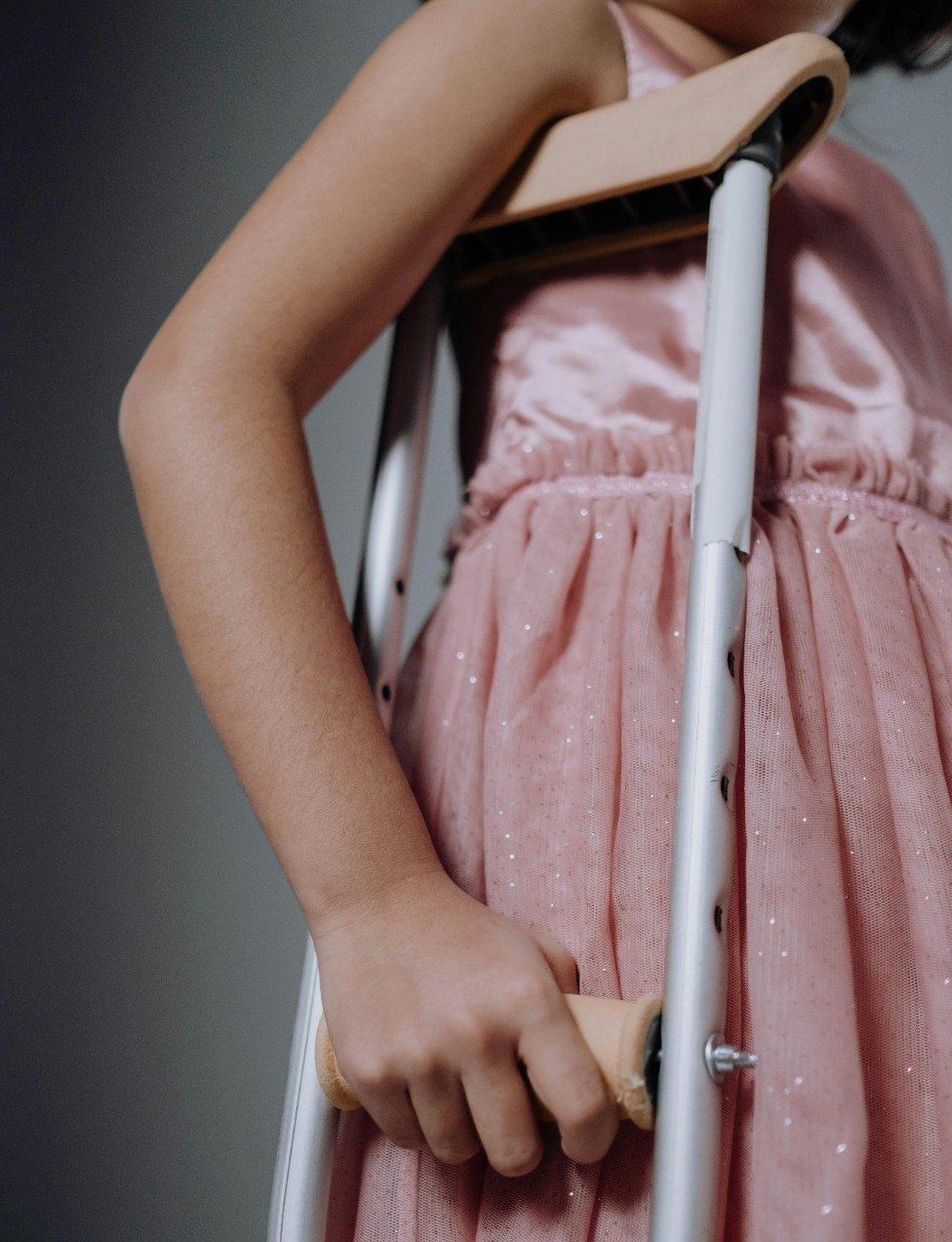 Dívka v růžových šatech o berlích