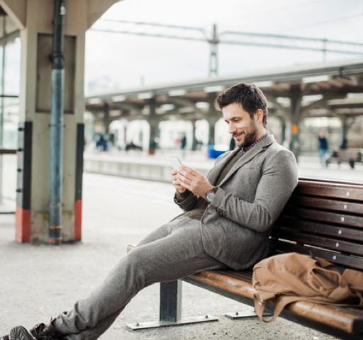 Muž na nádraží čte zprávu z mobilu